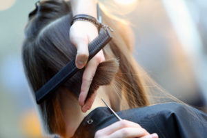 Hairdresser trimming brown hair with scissors